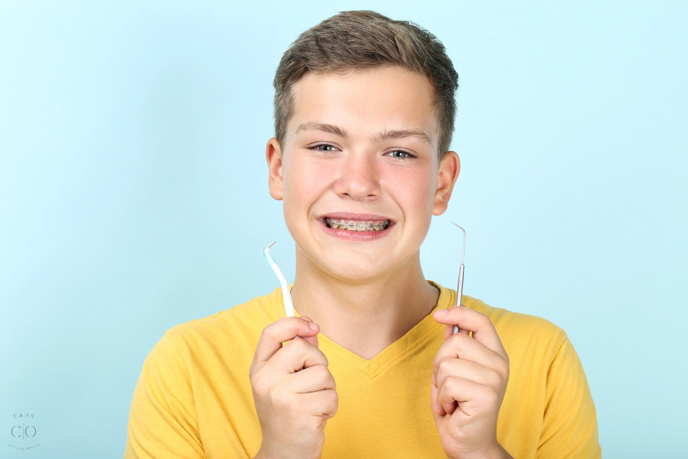 young man with metal braces toothbrush dentist tool - How to Floss with Braces in Fairview, TN